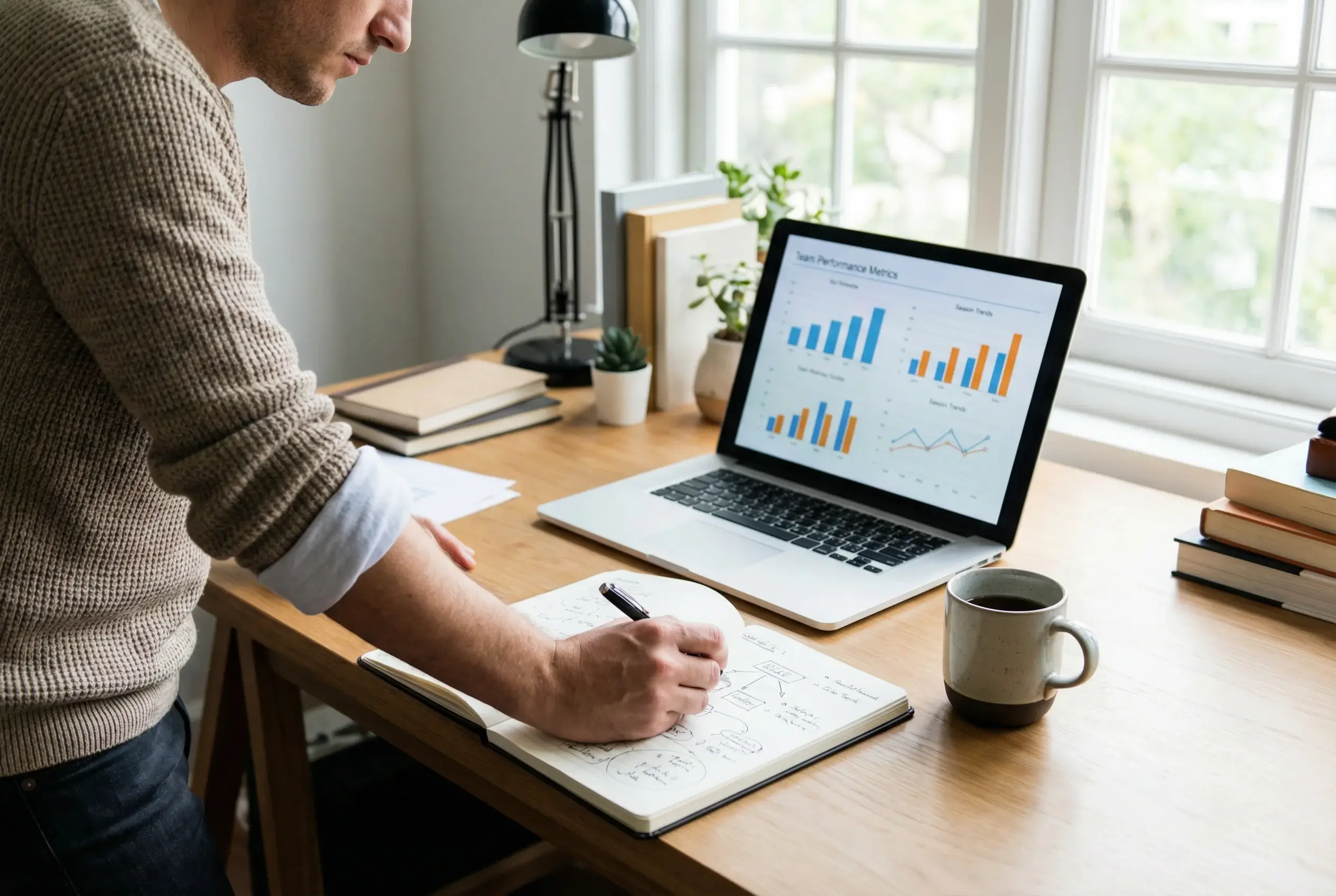 Persona che analizza statistiche di calcio su laptop con quaderno di appunti